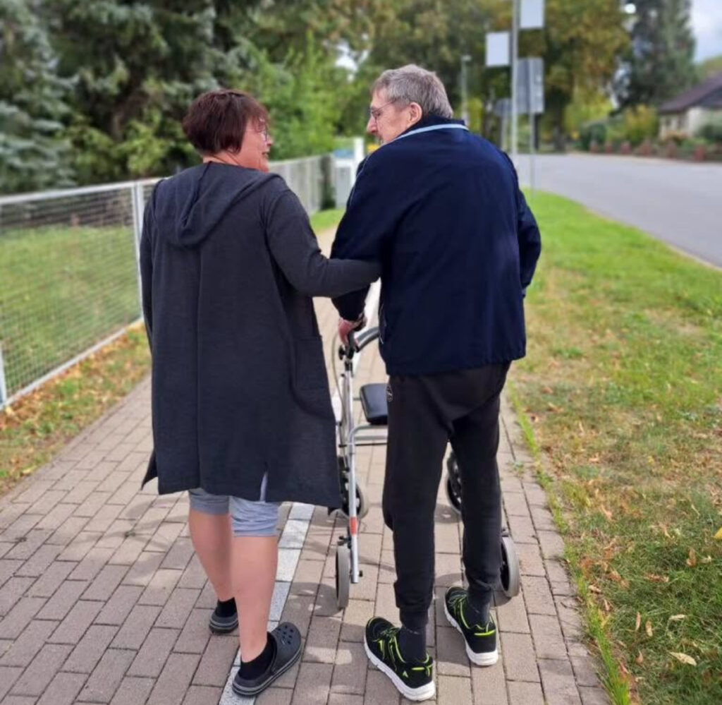 Pflegekraft begleitet Kunden beim Spaziergang