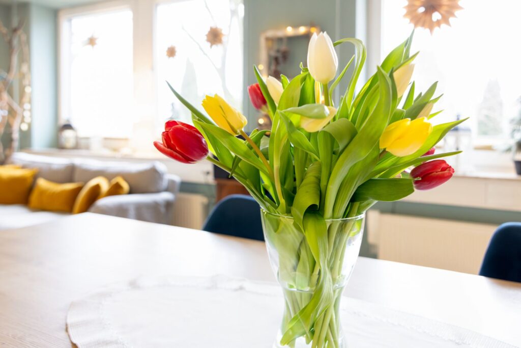 Bunter Tulpenstrauß in einer Glasvase auf einem Tisch im Wohnraum