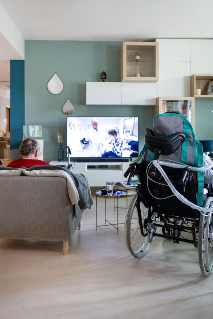 Kunde einer Intensivpflege-WG verbringt Zeit im Gemeinschaftsraum beim Fernsehen