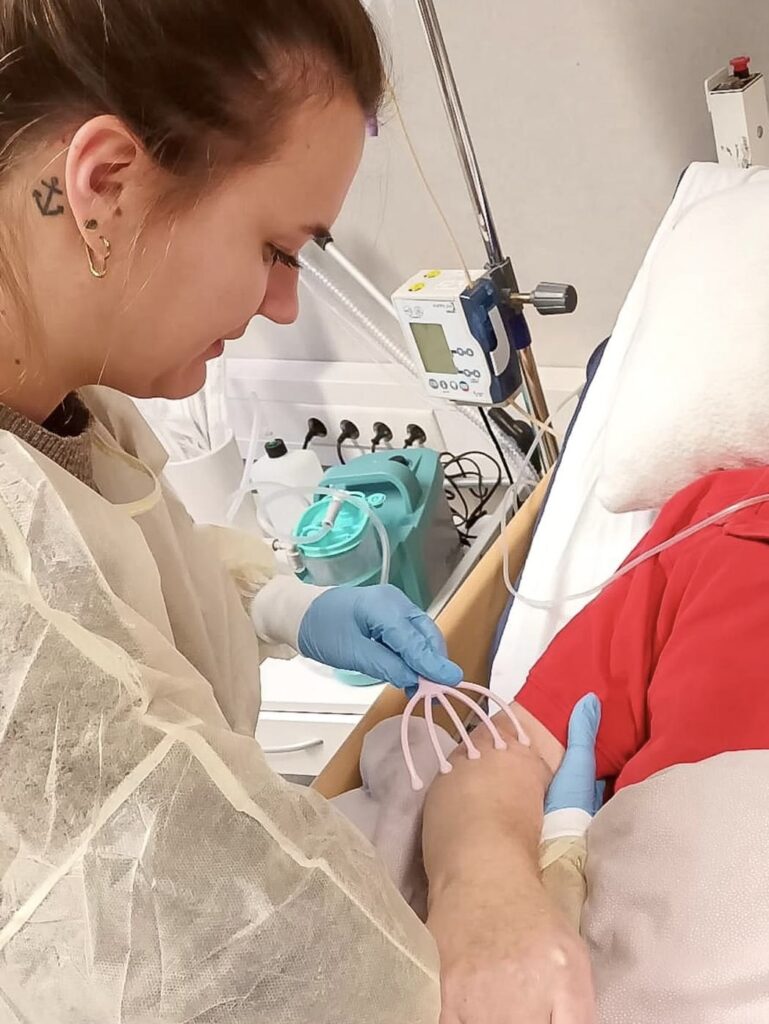 Fachkraft führt eine therapeutische Behandlung am Patienten in einer Intensivpflege-WG durch